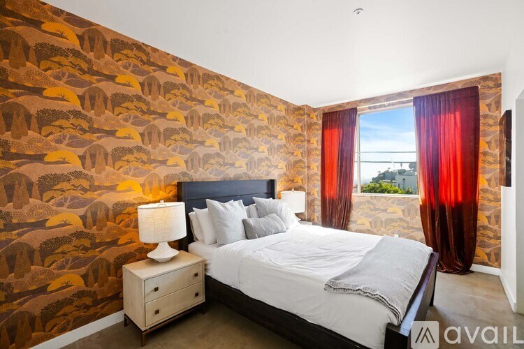 A bedroom with a bed, nightstand, and a wallpapered wall.