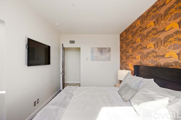 A bedroom with a large bed and a television on the wall.