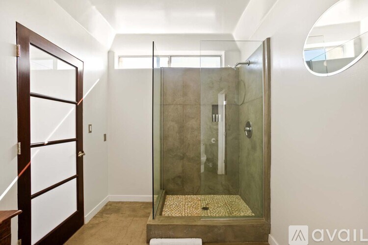 A bathroom with a walk-in shower and a round mirror on the wall.