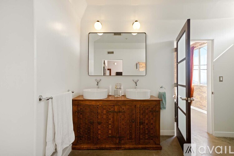 A bathroom with a wooden cabinet and a large mirror above it.