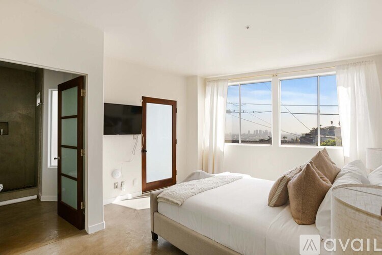 A bedroom with a large bed and a view of the city through the window.