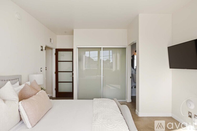 A bedroom with a bed, pillows, and a television.