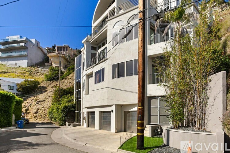 A modern building with a balcony and a green lawn in front.
