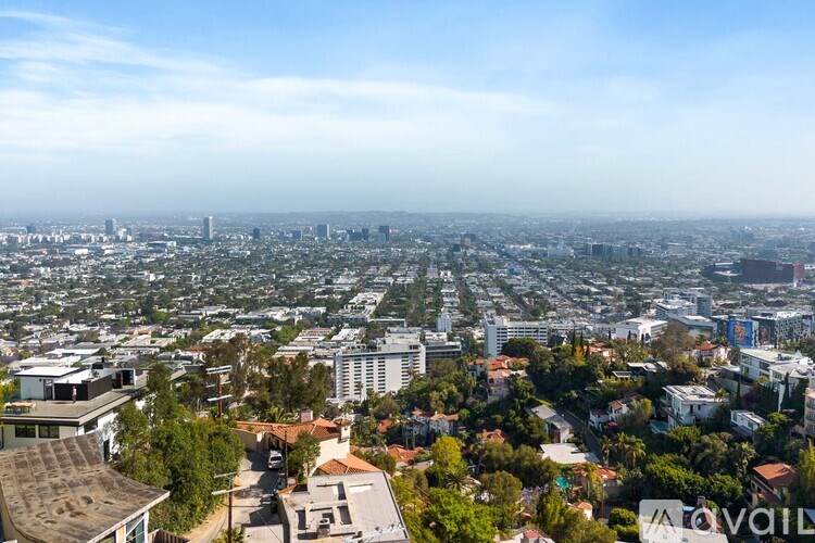 A white washing machine sits in a laundry room with a window showing a mountainous landscape.