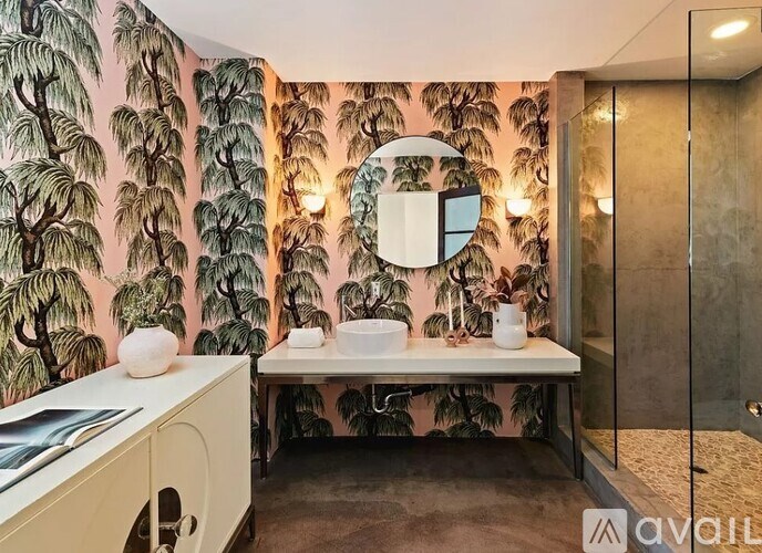 A bathroom with a sink, mirror, and wallpapered walls.