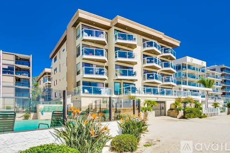 A modern multi-story building with balconies and a pool in the foreground.