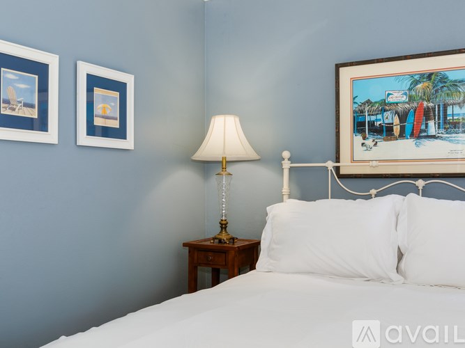 A bedroom with a bed, a lamp, and two pictures on the wall.