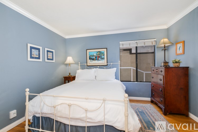 A bedroom with a white bed and a wooden dresser.