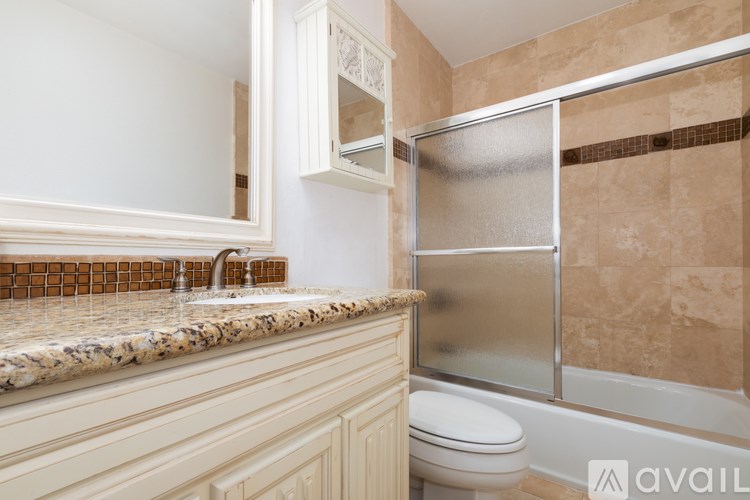 A bathroom with a marble countertop and a glass shower door.