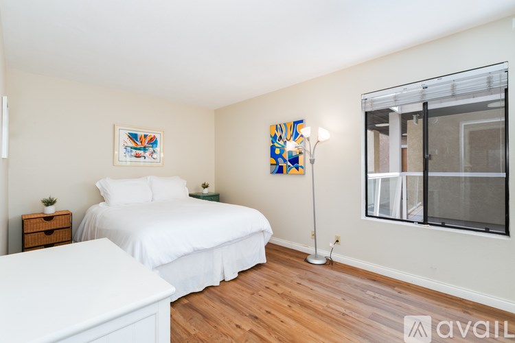 A bedroom with a white bed and a wooden floor.