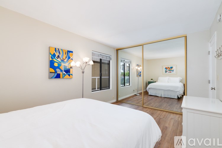 A bedroom with a large bed and a mirrored closet door.