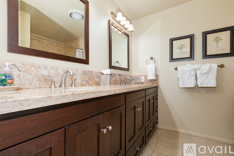 A bathroom with a marble countertop and wooden cabinets.
