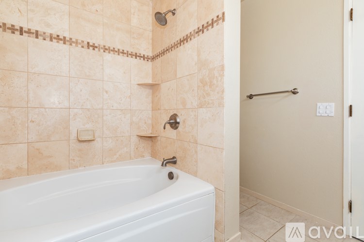 A bathroom with a white bathtub and tiled walls.