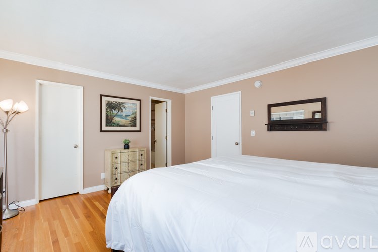 A bedroom with a large bed and a painting on the wall.