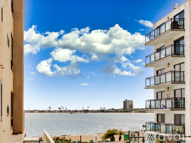 A view of a balcony overlooking a body of water with buildings and trees in the distance.