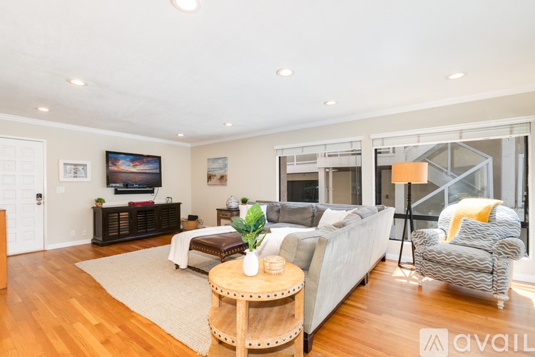 A living room with a grey couch, a wooden coffee table, and a television on the wall.
