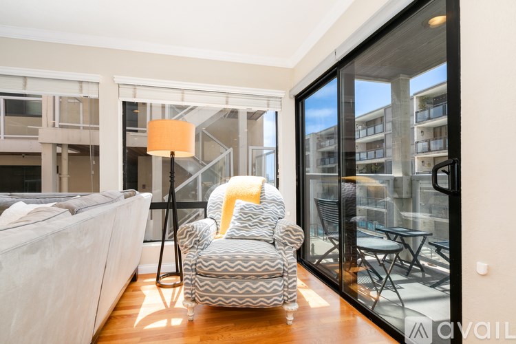 A living room with a grey sofa and a yellow pillow on a grey and white striped armchair.