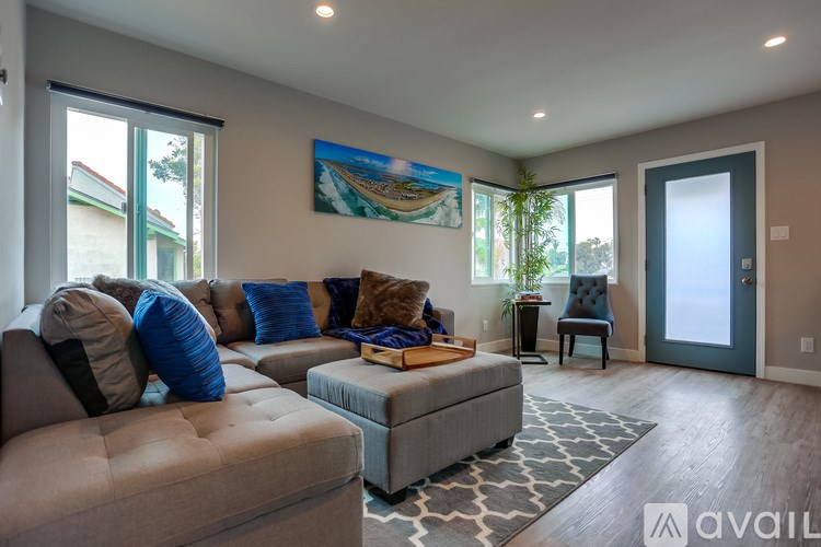 A living room with a grey sofa and a painting on the wall.
