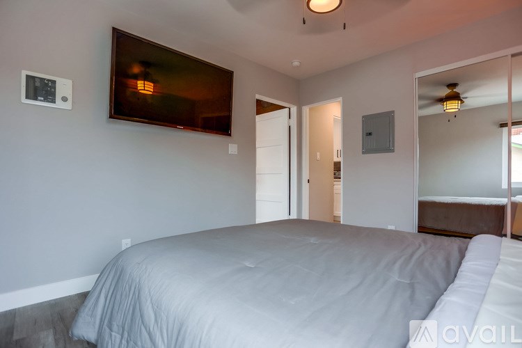 A bedroom with a large bed and a television mounted on the wall.