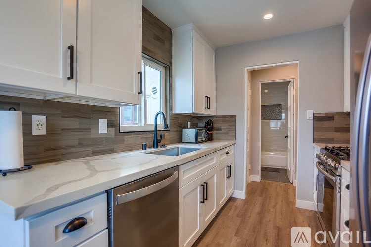 A kitchen with white cabinets and a marble countertop.