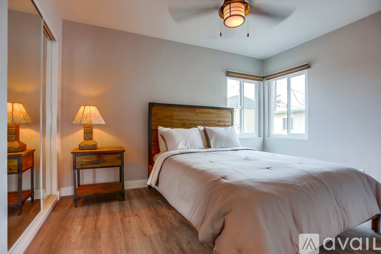 A bedroom with a bed, nightstands, and a ceiling fan.