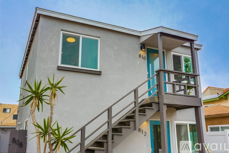 A modern two-story house with a balcony and stairs leading to the second floor.
