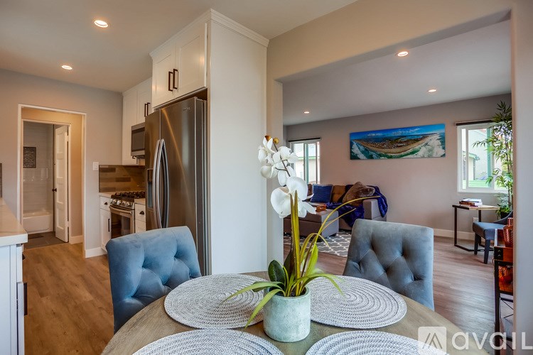 A modern kitchen with a dining table set with a vase of flowers in the middle.