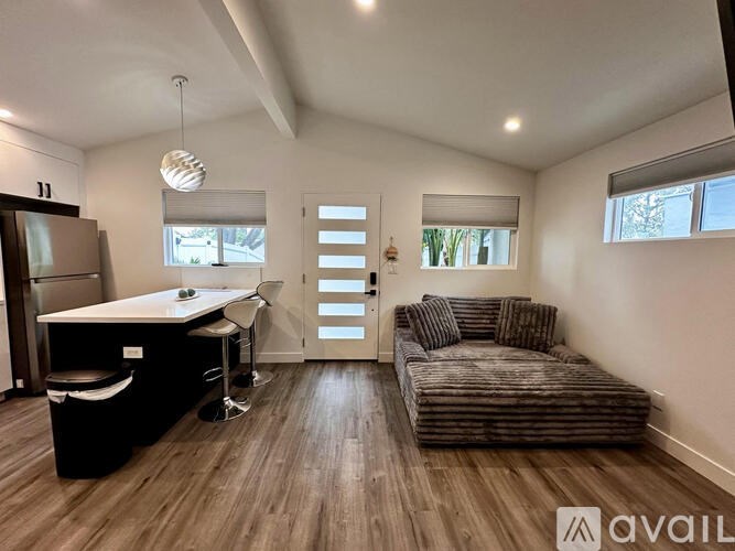 A living room with a couch, a dining table, and a kitchen area.