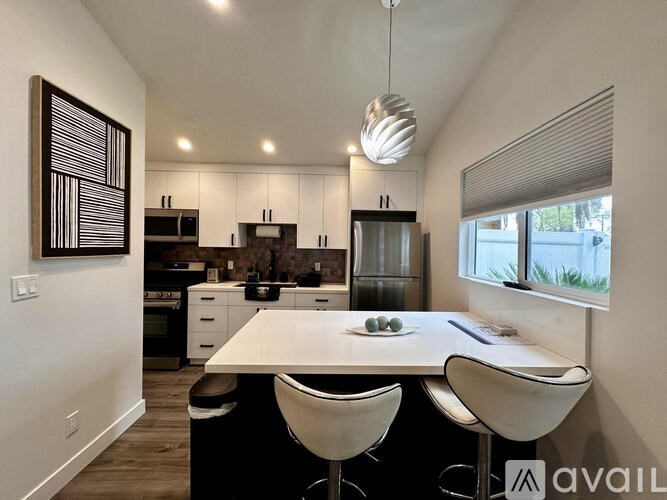 A modern kitchen with white cabinets and a dining table with chairs.