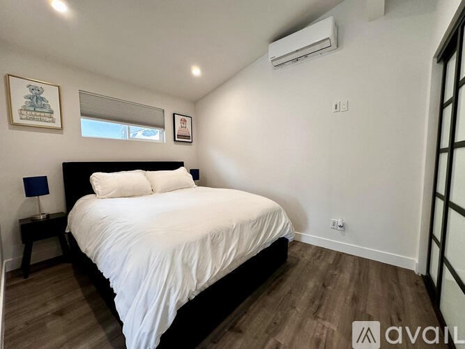 A bedroom with a bed, nightstand, and window.