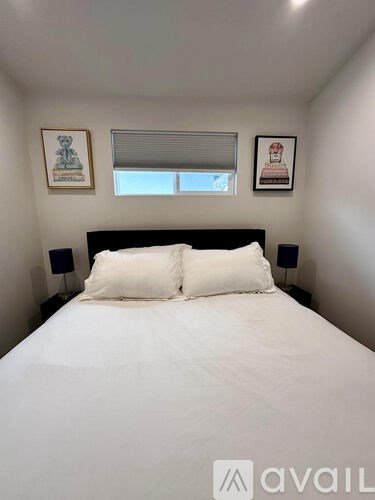 A bedroom with a bed, two pillows, and two framed pictures on the wall.