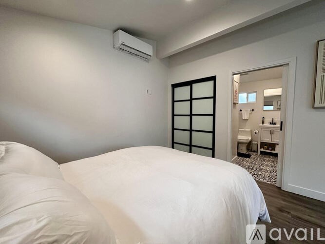 A bedroom with a bed, mirror, and a window with blinds.
