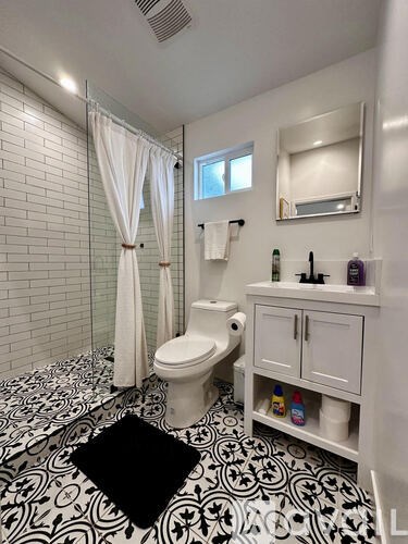 A white toilet with a white cabinet and a black and white floor.