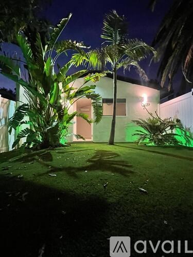 A house with a green lawn and trees at night.