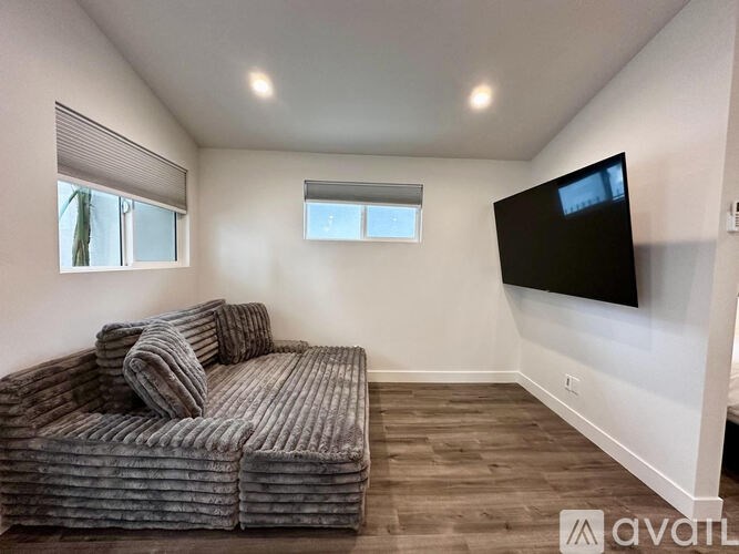 A living room with a grey couch and a flat screen TV mounted on the wall.