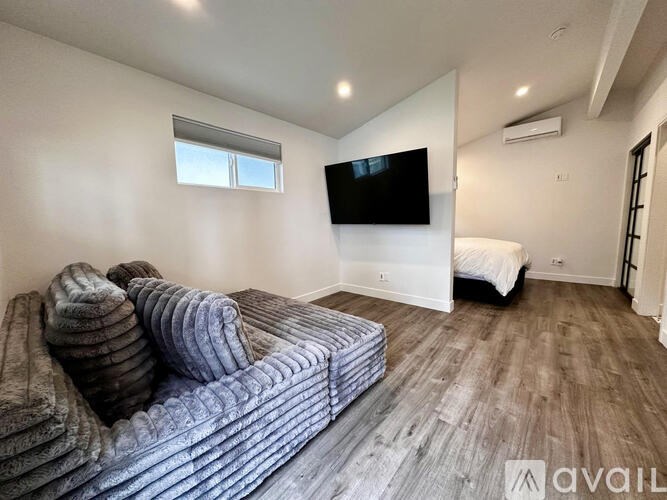 A living room with a grey couch and a flat screen TV mounted on the wall.
