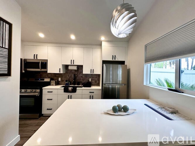 A modern kitchen with a white countertop and stainless steel appliances.