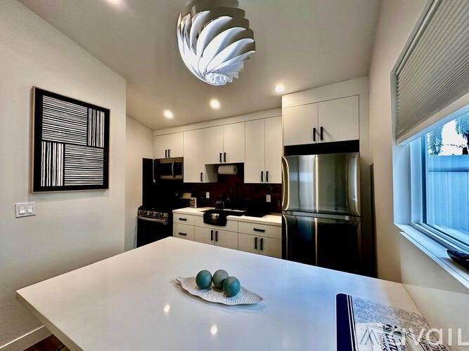 A modern kitchen with a white table and a framed picture on the wall.