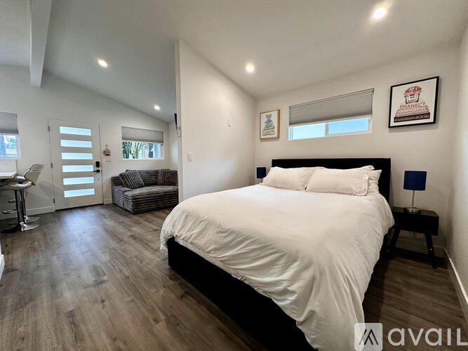 A bedroom with a large bed and a balcony with a chair.