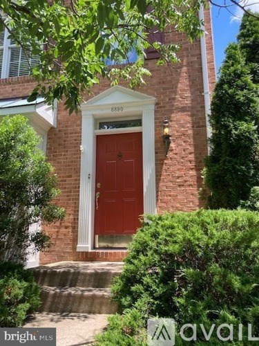 A red door is on the front of a brick house.