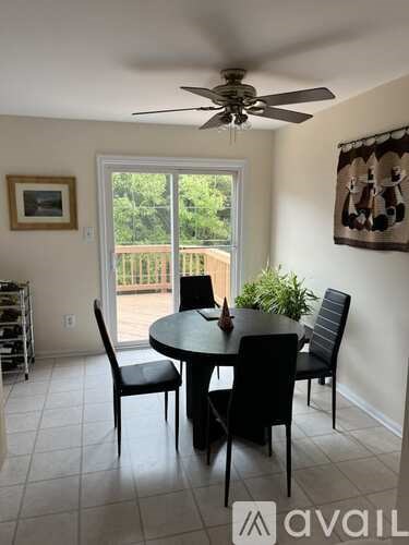 A dining room with a table and chairs and a ceiling fan.