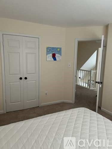 A bedroom with a white bed and a white door.