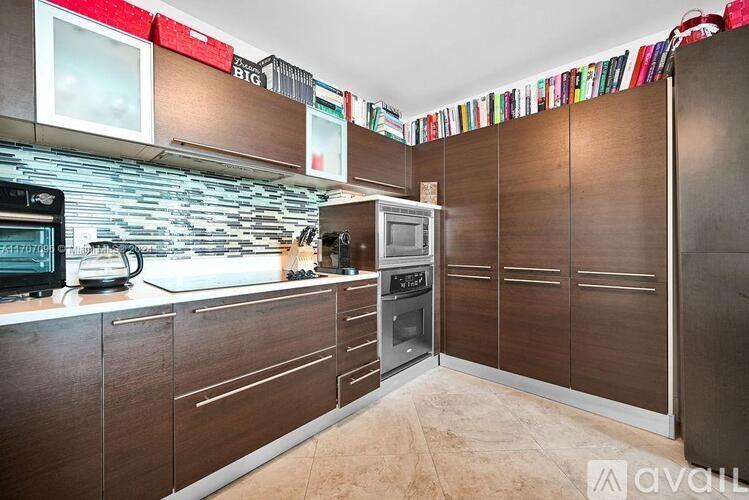 A kitchen with brown cabinets and a stone backsplash.