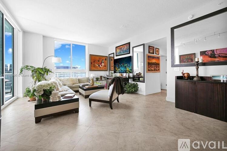 A living room with a large window, a sofa, a coffee table, and a chair.