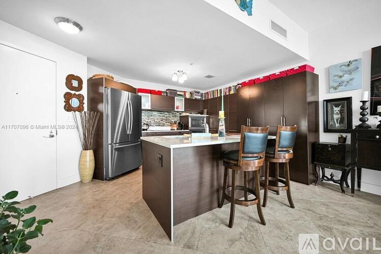 A kitchen with a bar stool and a fridge.