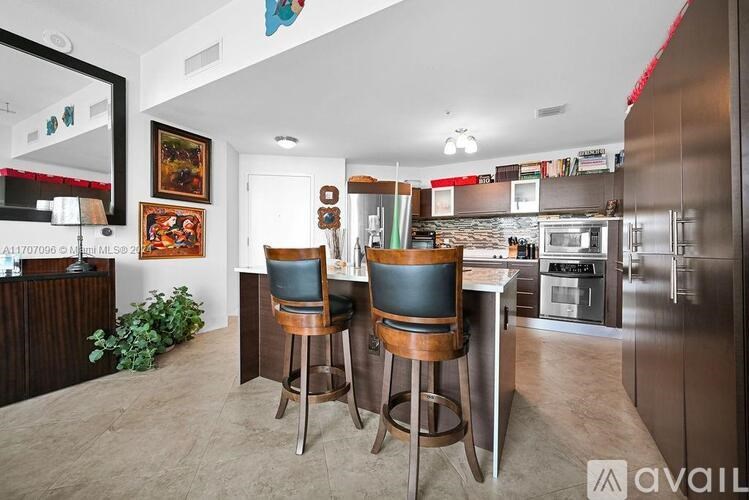 A kitchen with a bar stool and a chair in front of a counter.