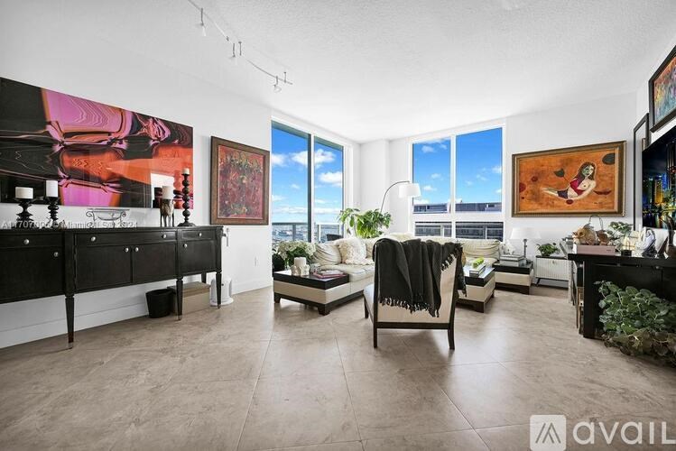 A living room with a black couch and a painting on the wall.