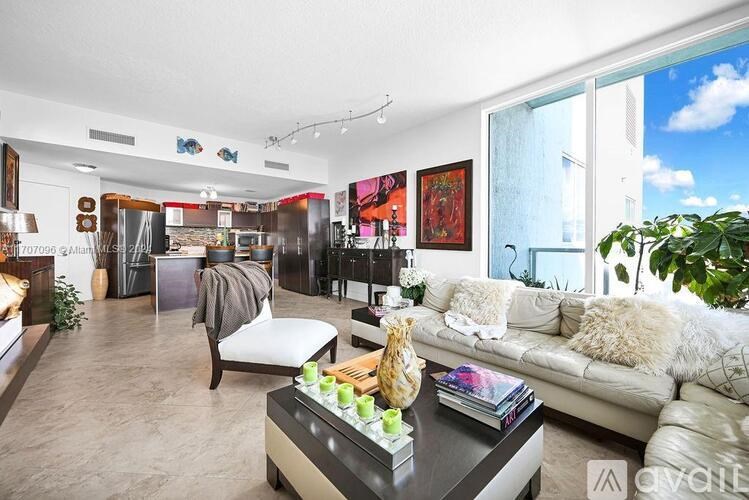 A living room with a white couch and a coffee table with a vase on it.