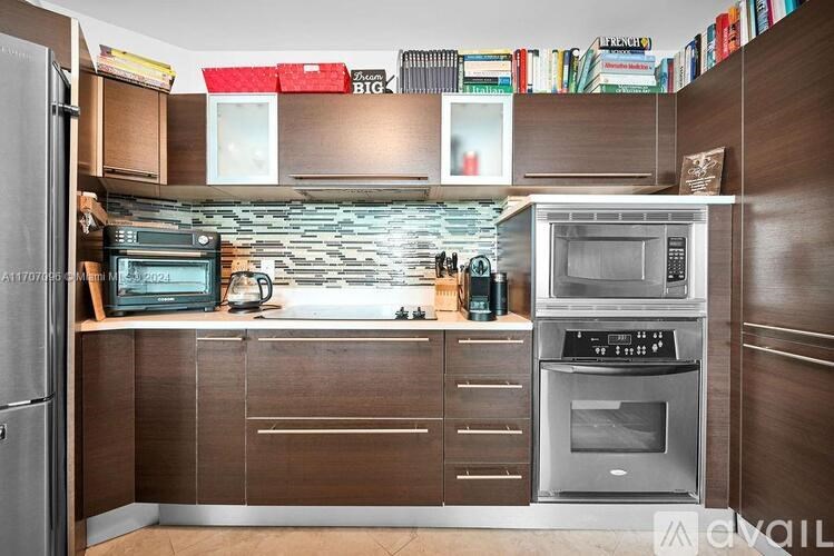 A kitchen with a refrigerator, oven, and microwave.