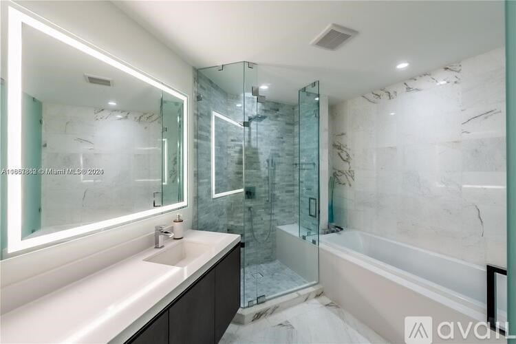 A bathroom with a marble wall and a glass shower stall.